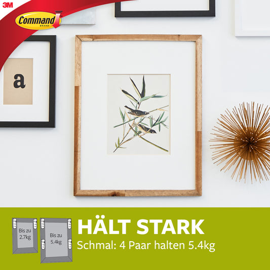 Ein gerahmter botanischer Druck hängt an einer weißen Wand, umgeben von anderen Rahmen und einem goldenen Akzent. Darunter steht ein Banner mit der Aufschrift "HÄLT STARK" und dem Hinweis, dass 3M Schmale Command™ Bilder-Montage Strips (M) 17207 bis zu 5,4 kg pro 4 Paare halten können.
