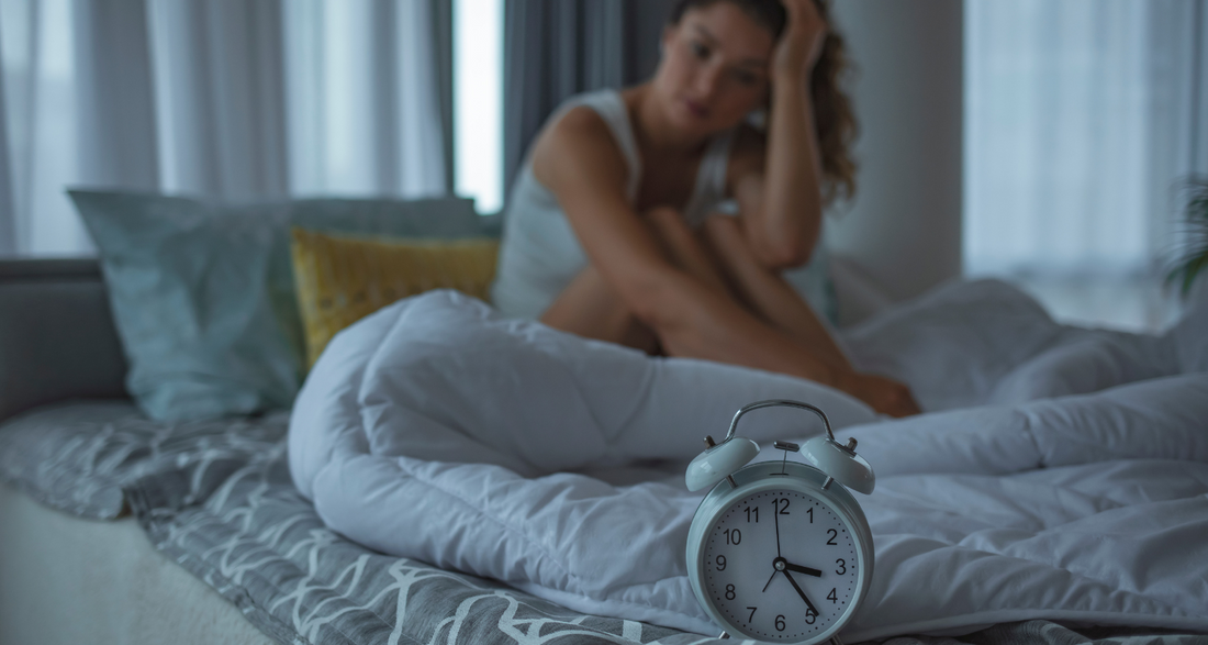 Frau im Bett sitzt vor dem Wecker