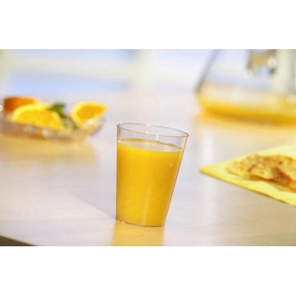Un bicchiere Starpak 40, PS 0,1 l Ø 5,5 cm · 7,5 cm bicchiere monouso trasparente è riempito con succo d'arancia su un tavolo chiaro. Sullo sfondo ci sono fette d'arancia e una brocca - ideale per feste ed eventi.
