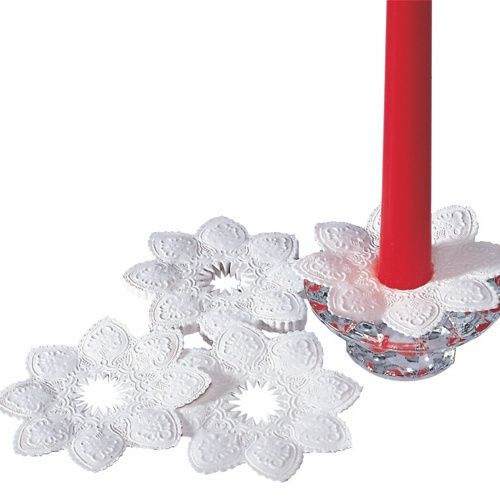 Si vedono tre maniche per candele rotonde, bianche PAPSTAR (Ø 10 cm, pellicola): una avvolta intorno a una candela rossa a punta in un portacandele di vetro, due sdraiate - e mostrano il loro design elegante e decorativo della PAPSTAR GmbH.