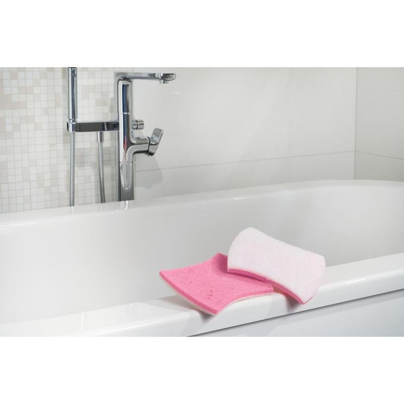 Viene mostrata una vasca da bagno bianca con rubinetti cromati. Sul bordo ci sono una spugna da bagno rosa e una spugna per la pulizia del bagno Scotch-Brite® Bath XXL di 3M Deutschland GmbH. Lo sfondo mostra piastrelle bianche con motivo a mosaico.