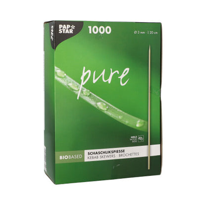Una scatola verde con la scritta "PAPSTAR Spiedini di legno pure" (Ø 3 mm, 20 cm, 1000 pezzi) della PAPSTAR GmbH mostra uno spiedino e un primo piano di una pianta verde fresca di rugiada.