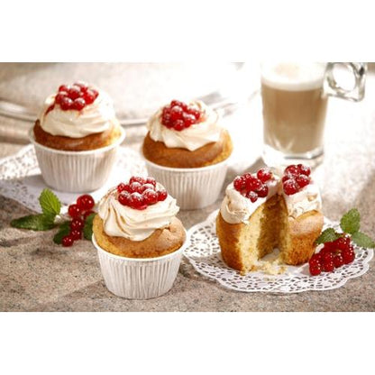 In PAPSTAR GmbH pirottini per muffin Ø 5 cm, 3,5 cm di altezza, bianchi (20 pezzi) ci sono quattro cupcake con glassa bianca e bacche rosse su un piano di lavoro. Uno è tagliato a metà. Sullo sfondo si vedono un rametto di menta e un bicchiere di latte.