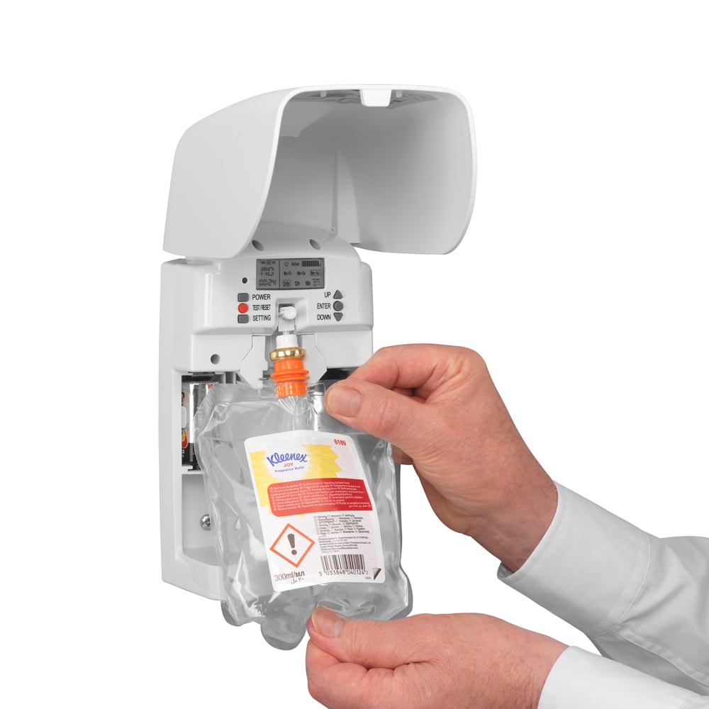 Una persona inserisce una ricarica Kleenex® Duft Joy (300 ml, Trasparente) della Kimberly-Clark GmbH in un dispenser a parete bianco, garantendo freschezza duratura con pulsanti e spie visibili.