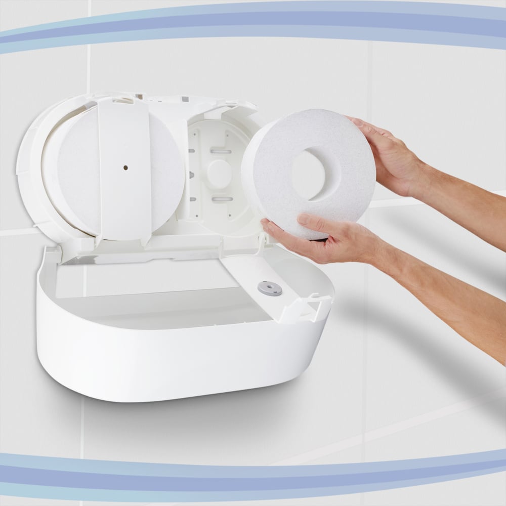 Una persona inserisce un rotolo grande di carta igienica Scott® Control™ - prelievo centrale, prodotto da Kimberly-Clark GmbH, in un distributore da parete bianco situato in un bagno piastrellato; una volta aperto, il distributore lascia visibili il vano e il mandrino: una soluzione ideale per gli ambienti professionali.