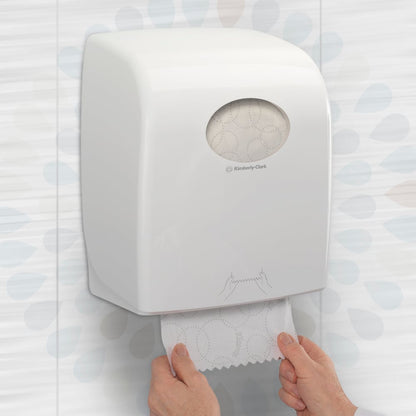 Una persona estrae un rotolo di asciugamani Kleenex® ULTRA™ (Bianco, 150m) di Kimberly-Clark GmbH da un dispenser a parete in un bagno, garantendo così l'asciugatura igienica delle mani. Confezione: 6 rotoli/scatola.