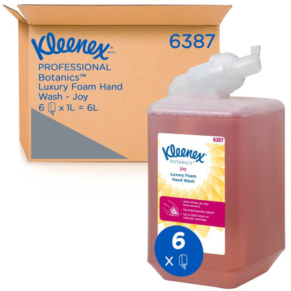 Una cassetta da 1 litro di Kleenex® Botanics™ Luxury Foam Hand Wash della Kimberly-Clark GmbH, di colore rosso, si trova davanti a una scatola "6387" che contiene sei cassette da 1 litro, con marchio visibile e ingredienti vegetali.