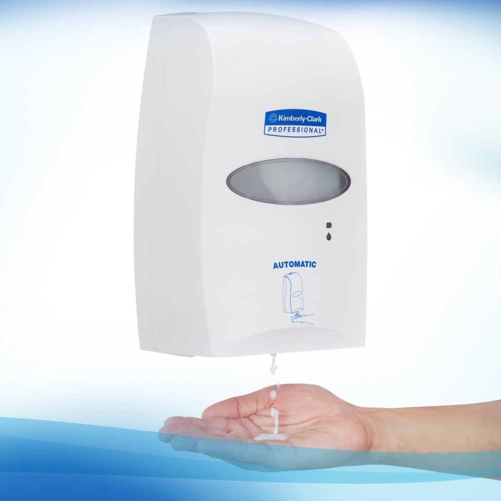 Un distributore a parete con la scritta "Kimberly-Clark GmbH" eroga schiuma disinfettante per le mani a base alcolica Scott® CONTROL (cassetta da 1,2L) per un'igiene ottimale delle mani. L'unità trasparente è raffigurata su sfondo bianco con accenti blu.