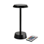 La lampada a LED wireless NOUR in grafite di Duni GmbH, con design moderno e base rotonda, viene mostrata accanto a un telecomando con pulsanti colorati - perfetta per la decorazione del tuo soggiorno.