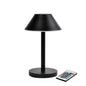 La lampada LED Zelda Midi di Duni GmbH in moderno design grafite con base rotonda e paralume conico si trova accanto a un telecomando con pulsanti colorati - la soluzione di illuminazione ideale ed efficiente dal punto di vista energetico.