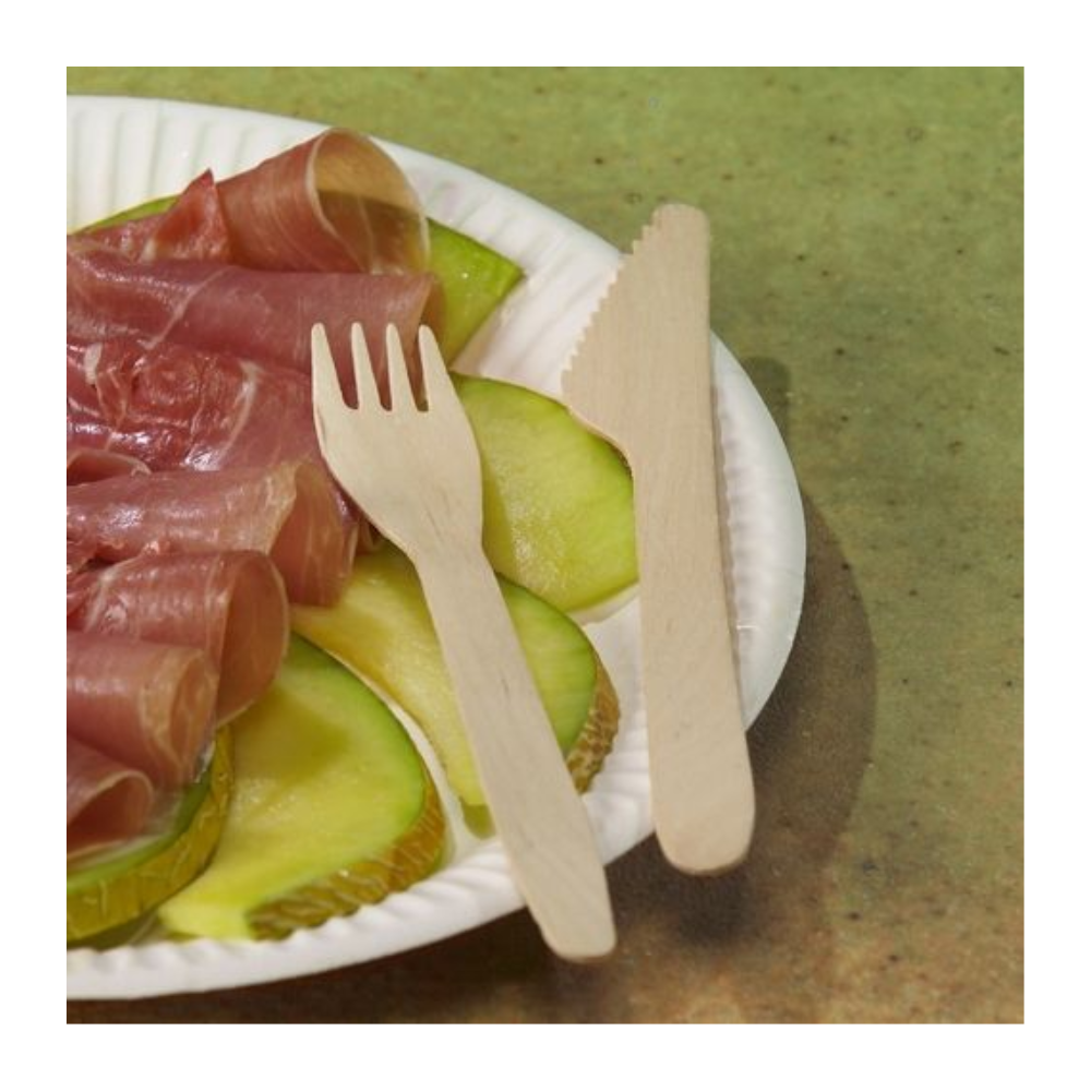 Un piatto di carta bianco con fette di mela verde e prosciutto, accanto a PAPSTAR forchette di legno "pure" 16,5 cm-ecologiche e stabili (100 pezzi)-da PAPSTAR GmbH, insieme a un coltello di legno, su sfondo verde.