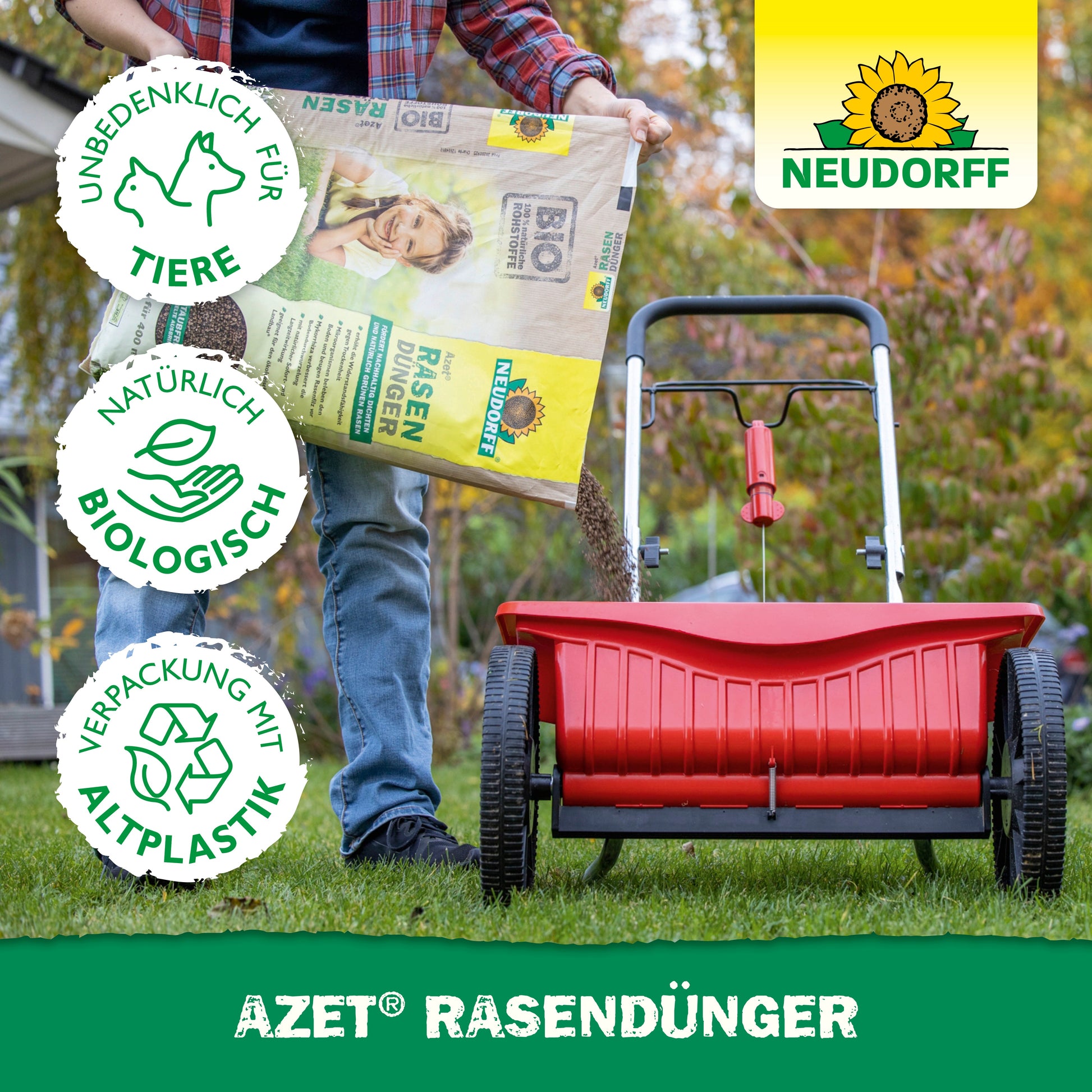 Eine Person füllt einen roten Streuer mit Neudorff Shop Azet RasenDünger 2,5-5 kg, um dichte Rasenflächen zu fördern. Drei Symbole zeigen an, dass er tierfreundlich, biologisch natürlich und aus recyceltem Kunststoff ist. Das Neudorff-Logo ist sichtbar.