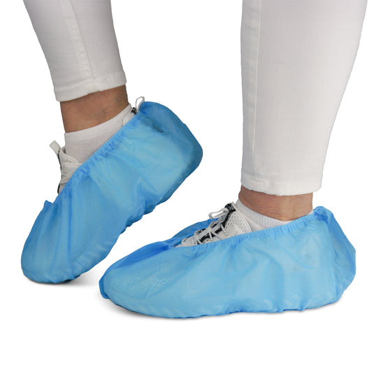 Una persona indossa pantaloni bianchi e scarpe da ginnastica con i copriscarpe ARNOMED ABS della ARNOWA GmbH. Questi copriscarpe monouso antiscivolo (confezioni da 100 pezzi) proteggono le scarpe e i pavimenti: sono ideali per ambienti in cui è richiesta l’igiene.