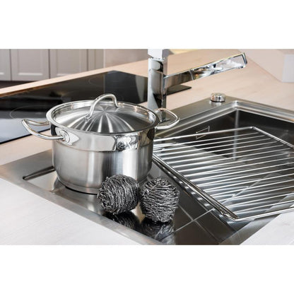 Una pentola in acciaio inossidabile con coperchio si trova nel lavandino accanto a due spirali in acciaio inossidabile Scotch-Brite® (3M Deutschland GmbH, 3 pezzi per confezione) e a un portapiatti - per una facile pulizia della cucina anche in presenza di sporco ostinato.
