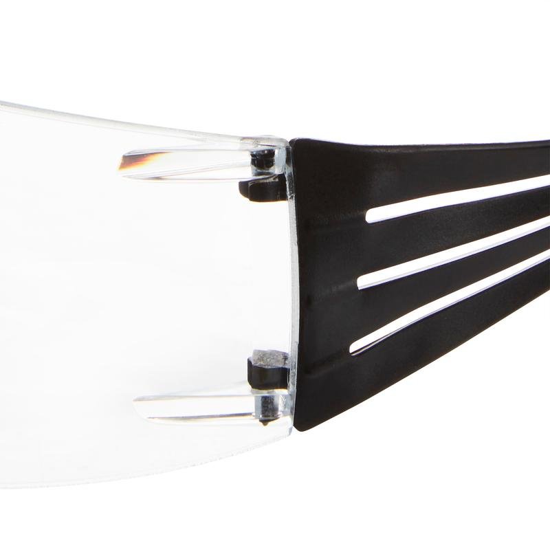 Primo piano dell'area della cerniera, dove una lente in plastica trasparente incontra un'asta nera degli occhiali protettivi da lettura 3M™ SecureFit™ di 3M Deutschland GmbH, con dettagli di connessione e design in evidenza.