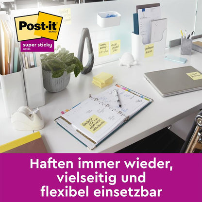Su un moderno tavolo da ufficio sono applicate le Post-it® Super Sticky Notes, Giallo (76x127 mm, 90 fogli/blocco, 14+2 blocchi gratuiti/confezione) di 3M Deutschland GmbH su varie superfici. Un logo Post-it appare in alto a sinistra e un testo tedesco in basso.
