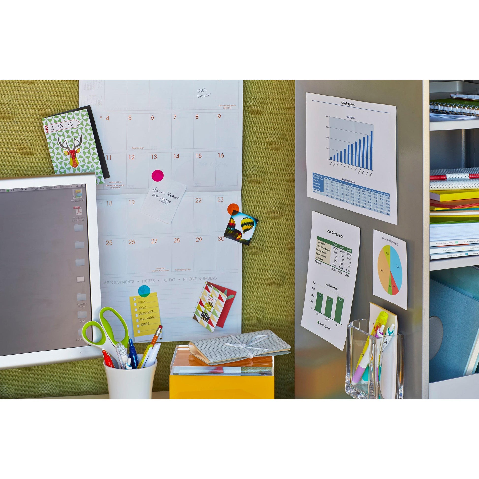 Ein Arbeitsbereich mit Computermonitor, Schere, Stiften, Ordnern und Organisationsmitteln verfügt über Tabellen, die mit Scotch-FIX™ Ablösbare Klebepads 301008C36-P (3M Deutschland GmbH), 11x15 mm, 36 Stück/Packung, am Schrank befestigt sind.