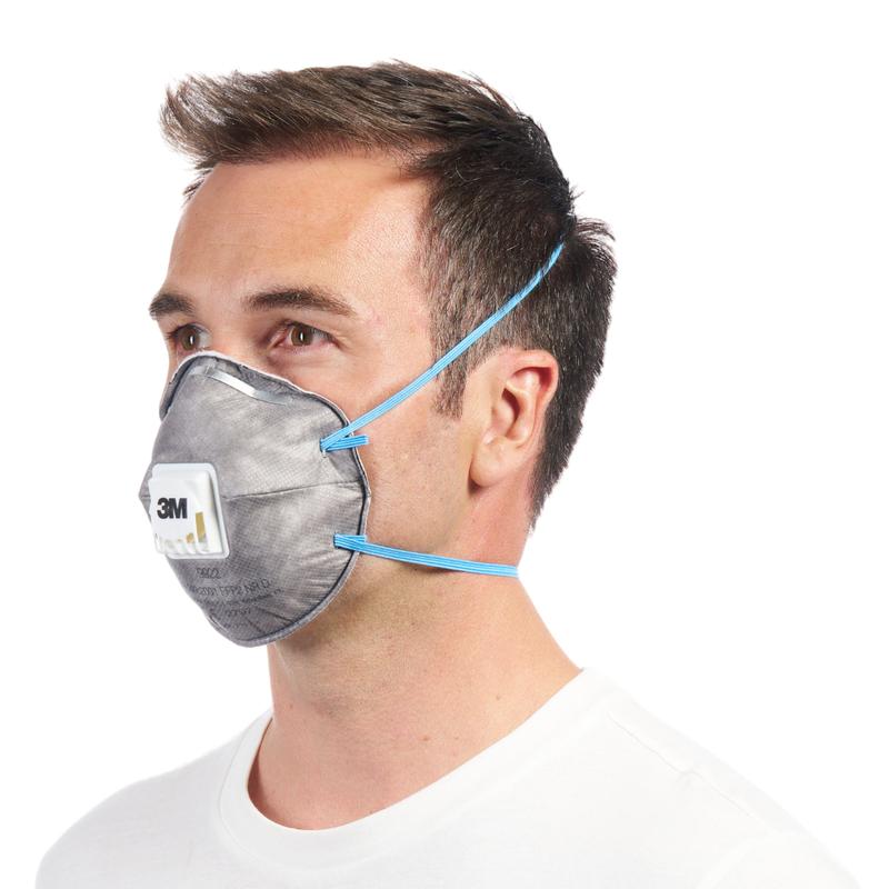 Una persona indossa una maschera antiparticolato 3M™ Cool Flow™ 9922 FFP2 con cinghie blu e ventilazione di 3M Deutschland GmbH, che copre naso e bocca, da un'angolazione laterale su uno sfondo bianco uniforme.