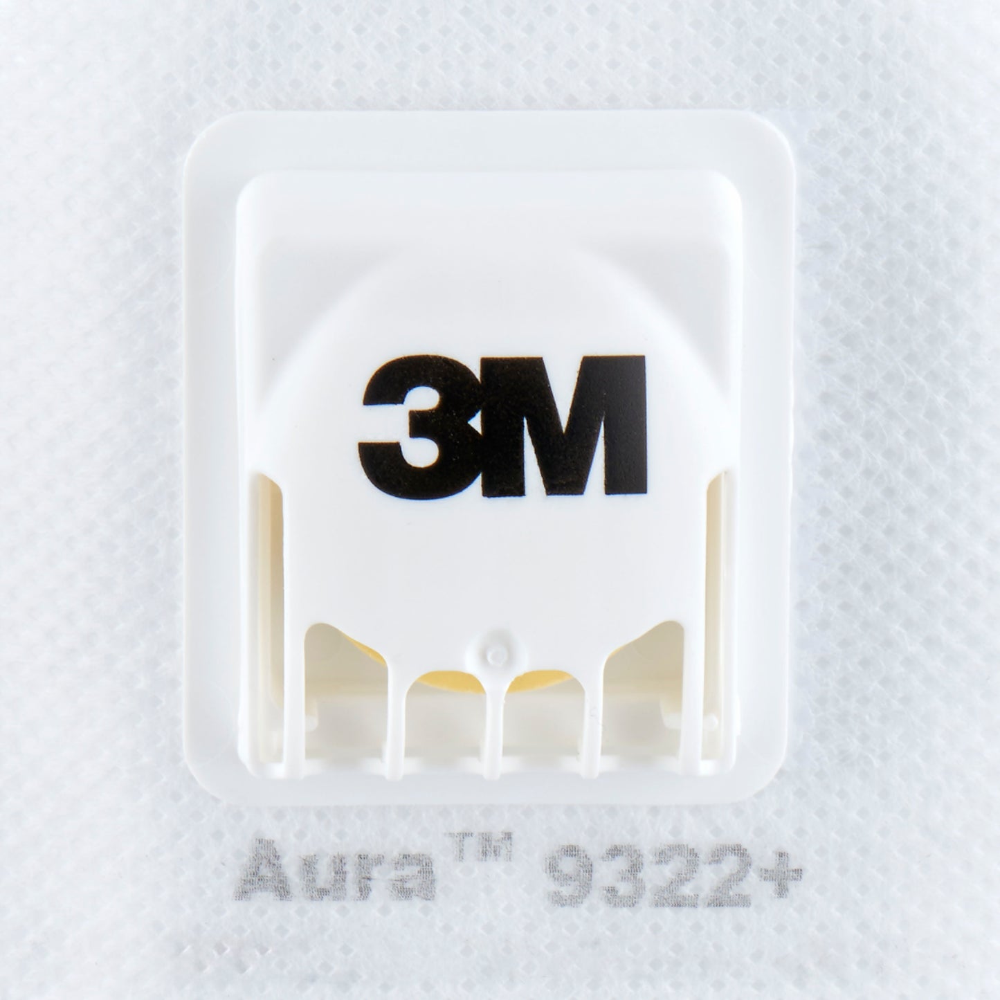 Primo piano di una maschera antiparticolato bianca 3M™ Aura™ Comfort Cool Flow™ 9322+, FFP2, con valvola di 3M Deutschland GmbH, che mostra la valvola del marchio e il testo "Aura 9322+" sul tessuto della maschera.