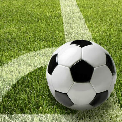 Un pallone da calcio bianco e nero si trova su un prato verde vicino a una linea bianca - ideale per una decorazione da tavola sportiva con PAPSTAR 20 tovaglioli, 33x33 cm, 3 veli, set da 4 di PAPSTAR GmbH per il tuo prossimo evento.