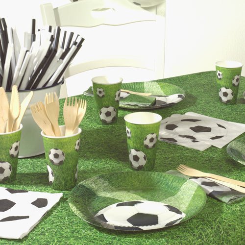 Una tavola da festa è apparecchiata con PAPSTAR tovaglioli a 3 veli da calcio (20 tovaglioli, 33x33 cm, Design Set 4), cannucce a righe bianco e nero, posate in legno in un portaposate e una tovaglia verde a forma di prato. Marca: PAPSTAR GmbH.