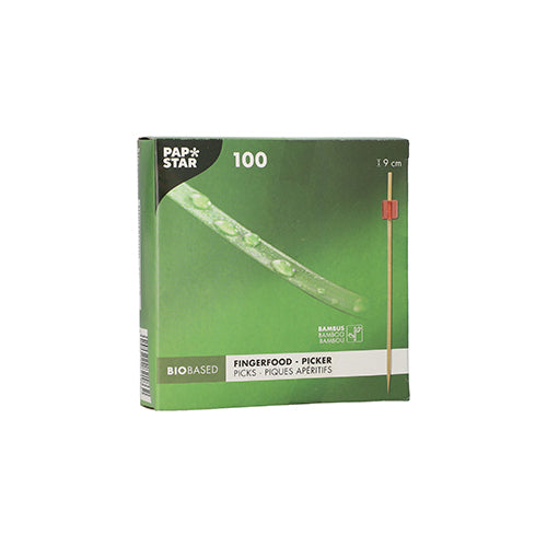 La scatola verde "PAPSTAR 100 Fingerfood - Picker" della PAPSTAR GmbH contiene 100 bastoncini di bambù di 9 cm ciascuno. La confezione biobased mostra un bastoncino con punta rossa, ideale per servire spiedini di fingerfood in ogni evento.