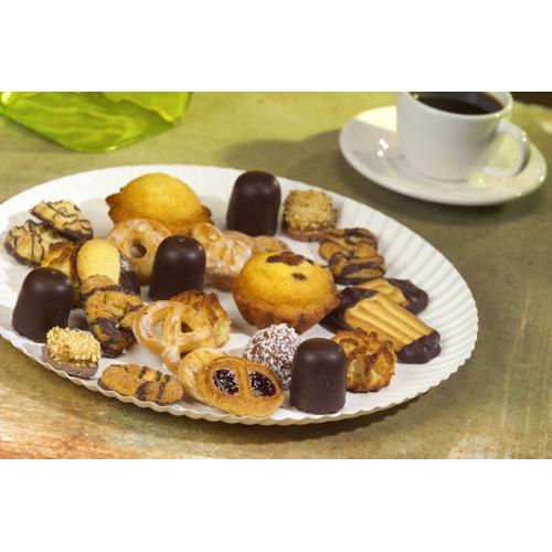 Un PAPSTAR piatto rotondo Ø 32 cm, bianco, in cartone "pure" di PAPSTAR GmbH con pasticcini e praline si trova accanto a una tazza da caffè bianca su un tavolo. Sullo sfondo si vede un tovagliolo verde.