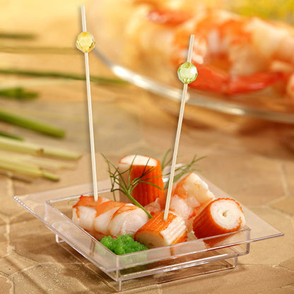 In una ciotola quadrata trasparente di plastica ci sono imitazioni di surimi, uova di pesce verdi e aneto, serviti con due PAPSTAR 100 Fingerfood - Picker della PAPSTAR GmbH con punte rotonde per una facile presa.