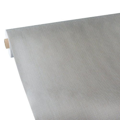 Una tovaglia Starpak parzialmente srotolata, simile al tessuto, tessuto non tessuto "soft selection plus" mostra la sua superficie liscia e flessibile di colore grigio chiaro con una colorazione uniforme; è dotata di un nucleo in cartone ed è prodotta da Starpak.