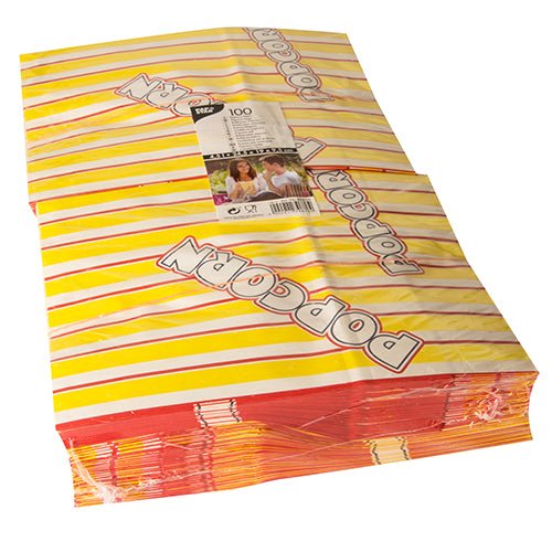 È raffigurata una pila di PAPSTAR 100 sacchetti di popcorn, sostituti della pergamena resistenti al grasso a strisce giallo-rosse con la stampa inclinata "POPCORN", con un'etichetta di imballaggio visibile della PAPSTAR GmbH sopra.