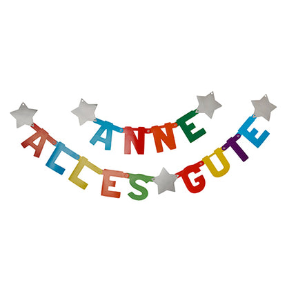 Due PAPSTAR catene di saluti personalizzabili della PAPSTAR GmbH sono appese come decorazione allegra: sulla superiore c'è scritto "ANNE", su quella inferiore "TANTI AUGURI". Entrambe sono dotate di lettere di carta colorate e personalizzabili e stelle bianche. 1 set in scatola pieghevole.