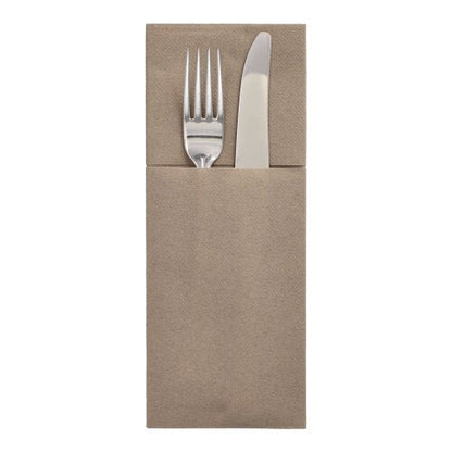 Una forchetta e un coltello d'argento si trovano in una tasca per posate Starpak 100, Airlaid 40 cm x 48 cm con piega per posate, creando così un'elegante apparecchiatura su uno sfondo bianco semplice.