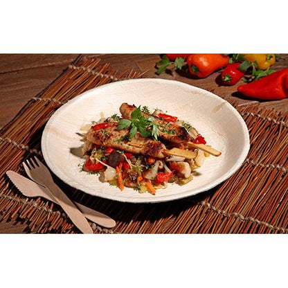 Spiedini di pollo alla griglia con padellata di verdure colorate vengono serviti su un PAPSTAR 6 piatti, foglia di palma „pure“ rotondi di PAPSTAR GmbH - stoviglie ecologiche, presentate con stile su una base intrecciata con posate in legno e peperoni freschi in vista.