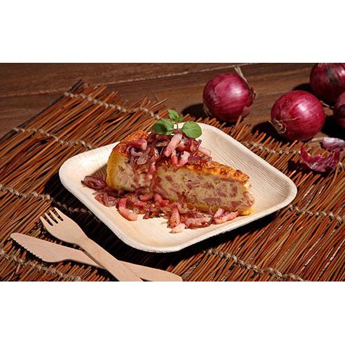 Un pezzo di tortilla spagnola con cipolle rosse viene servito su un piatto quadrato "Pure" della PAPSTAR GmbH dal set da 6 PAPSTAR, accompagnato da coltello e forchetta di bambù. Sullo sfondo si vedono cipolle rosse con la buccia su un tappetino intrecciato.