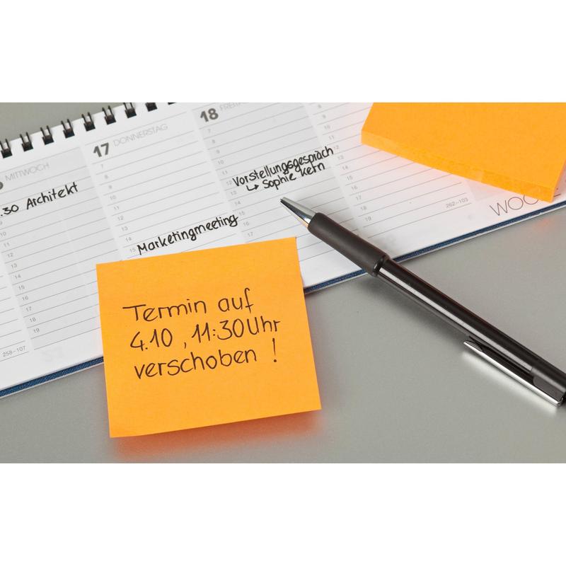 Una penna si trova su un planner aperto accanto a due foglietti Post-it® arancioni (76 mm x 76 mm, 100 fogli/blocco, 100% PEFC) della 3M Deutschland GmbH; un foglietto sposta un appuntamento al 4 ottobre alle 11:30 in lingua tedesca. Annotazioni scritte a mano appaiono nel planner.