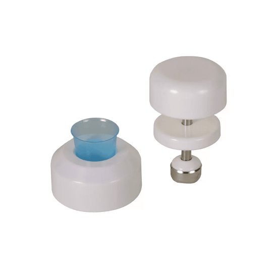 Su uno sfondo bianco sono visibili due utensili da cucina bianchi in plastica. L’utensile a sinistra ha una forma cilindrica con un inserto in plastica blu, mentre quello a destra è un pestello per compresse AMPri per bicchieri dosatori della AMPri Handelsgesellschaft mbH, costituito da due dischi bianchi collegati da un’asta in acciaio inossidabile con una base metallica.