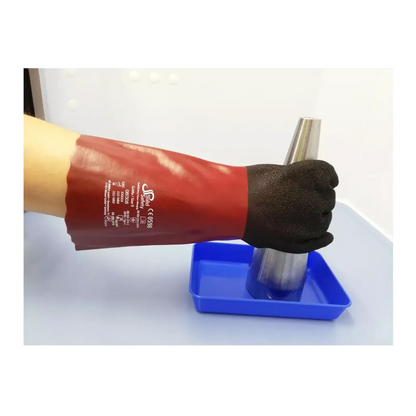 Una persona indossa un guanto rosso AMPri SolidSafety Chem MaxGrip con dita nere e marcature bianche e tiene un cono metallico sopra un vassoio blu. Il guanto, noto per la sua protezione contro gli acidi e la sua resistenza all'abrasione, si distingue dallo sfondo semplice e chiaro.