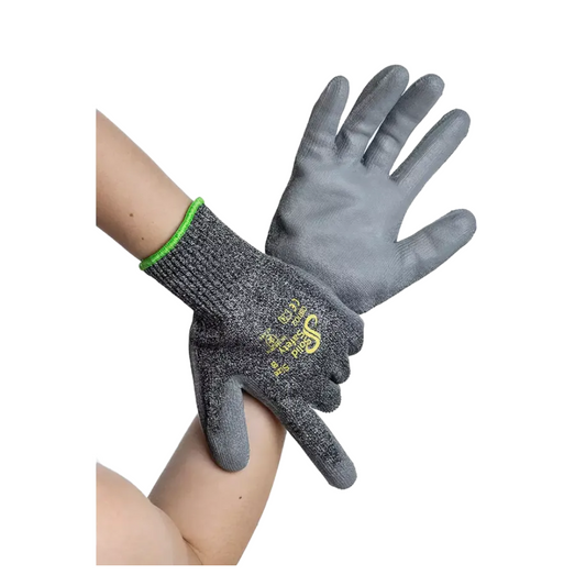 Zwei Hände tragen AMPri SolidSafety Cut High Schnittschutzhandschuhe, graue Arbeitshandschuhe aus schnittfestem Material. Diese Handschuhe der AMPri Handelsgesellschaft mbH weisen eine strukturierte Oberfläche mit gelb-weißem Text auf der Rückseite auf und haben einen grünen Rand am Handgelenk, der sowohl Haltbarkeit als auch Schutz bietet.