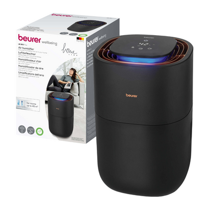Sulla confezione è raffigurato un umidificatore nero Beurer LB 300 della Beurer GmbH con un pannello di controllo digitale sulla parte superiore. La confezione mostra un marchio e l'immagine di una donna rilassata, indicando che il prodotto è destinato all'uso domestico. Il testo multilingue evidenzia i vantaggi del prodotto per un'aria interna igienica.