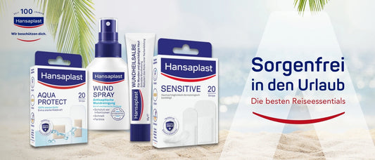 Werbebanner von Hansaplast mit dem Slogan ‚Sorgenfrei in den Urlaub – Die besten Reiseessentials‘. Zu sehen sind vier Hansaplast-Produkte im Vordergrund auf Sand vor tropischem Hintergrund mit Palmen: AQUA PROTECT Pflaster (20 Stück, wasserdicht), WUNDSPRAY (antiseptische Wundreinigung), WUNDHEILSALBE (zur Heilung geschädigter Haut) und SENSITIVE Pflaster (20 Stück, hautverträglich). Links oben das Hansaplast-Logo mit dem Hinweis ‚Seit 100 Jahren – Wir beschützen dich‘.