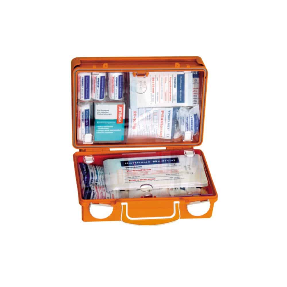 Una cassetta di pronto soccorso Holthaus Medical QUICK aperta, prodotta da Holthaus Medical GmbH & Co. KG, contiene vari strumenti medici, tra cui materiale per bendaggi, cerotti adesivi, salviette antisettiche e tamponi medici. Gli articoli sono ordinatamente disposti in scomparti nella cassetta realizzata secondo DIN 13157, in resistente plastica ABS.