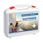 Una cassetta di pronto soccorso Holthaus Nautisave® bianca con accenti rossi, etichettata con "Holthaus Medical NAUTISAVE Erste Hilfe an Bord / First Aid". La parte anteriore dello zaino mostra un'immagine di due persone su una barca a vela al tramonto, rendendolo ideale per ambienti marittimi.