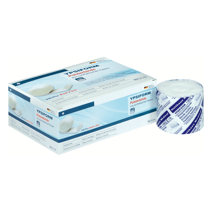 Una scatola di Holthaus Ypsiform Polsterbinde è raffigurata accanto a un rotolo non confezionato della benda. La confezione è prevalentemente bianca con accenti blu e testo, inclusi dettagli del prodotto e marchio di Holthaus Medical GmbH & Co. KG. Questa benda di alta qualità offre un eccellente supporto per vari scopi medici.