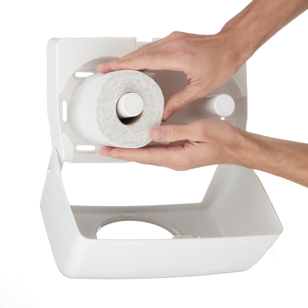 Eine Person legt eine neue Rolle Kleenex® Toilettenpapierrollen Kleinrollen aus einer 8 x 12-Packung der Kimberly-Clark GmbH bei geöffnetem Deckel in einen weißen Kunststoffspender ein.