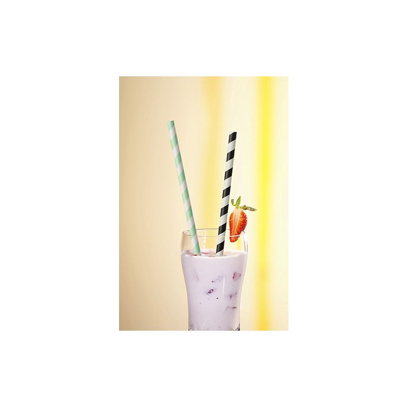 Un bicchiere di frappè viola con ghiaccio, sormontato da una fragola e due cannucce di PAPSTAR 100 cannucce di carta Ø 6 mm - una a strisce verde-bianco, una a strisce nero-bianco - di PAPSTAR GmbH, davanti a uno sfondo giallo dolcemente illuminato.