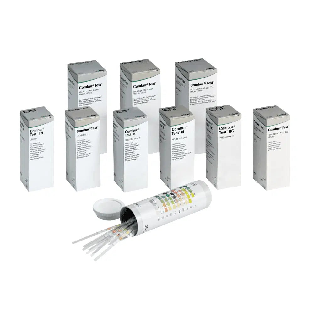 Dietro un contenitore cilindrico aperto con coperchio si nascondono nove scatole con l'etichetta "Combur®" di Servoprax GmbH, ciascuna contenente 100 strisce reattive per urine Roche. Sul lato del contenitore è fissata una tabella multicolore, perfetta per eseguire un test rapido.