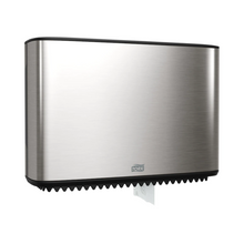 Ein Tork Xpress Spender für Mini-Jumbo-Toilettenpapier, Teil der Image Line, ist elegant an der Wand montiert. Dieser Spender aus Edelstahl hat ein schlankes rechteckiges Design, an dessen Unterseite ein kleiner Abschnitt weißen Papiers sichtbar ist. Die Marke „TORK – Essity Professional Hygiene Germany GmbH“ ist auf der Vorderseite deutlich zu sehen.