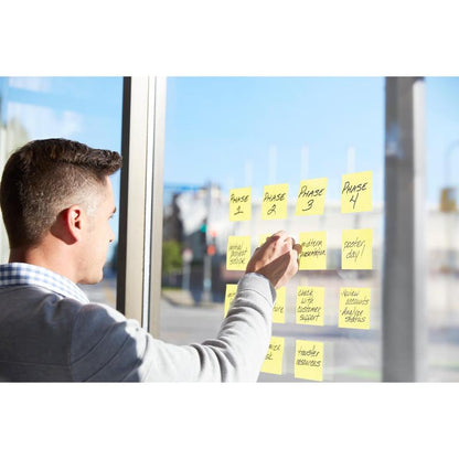 Una persona organizza a mano le fasi del progetto come "Fase 1" e "Presentazione intermedia" su una finestra con i Post-it® Super Sticky Z-Notes, Giallo (76x127mm, 90 fogli/blocco), certificato PEFC in confezione di cartone della 3M Deutschland GmbH.
