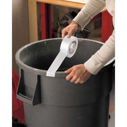 Eine Person klebt Scotch® Universal Klebeband 2904 (10 m x 48 mm) von 3M Deutschland GmbH auf den Rand eines großen grauen Plastikmülleimers, im Hintergrund sind Werkzeuge und Regale zu sehen.