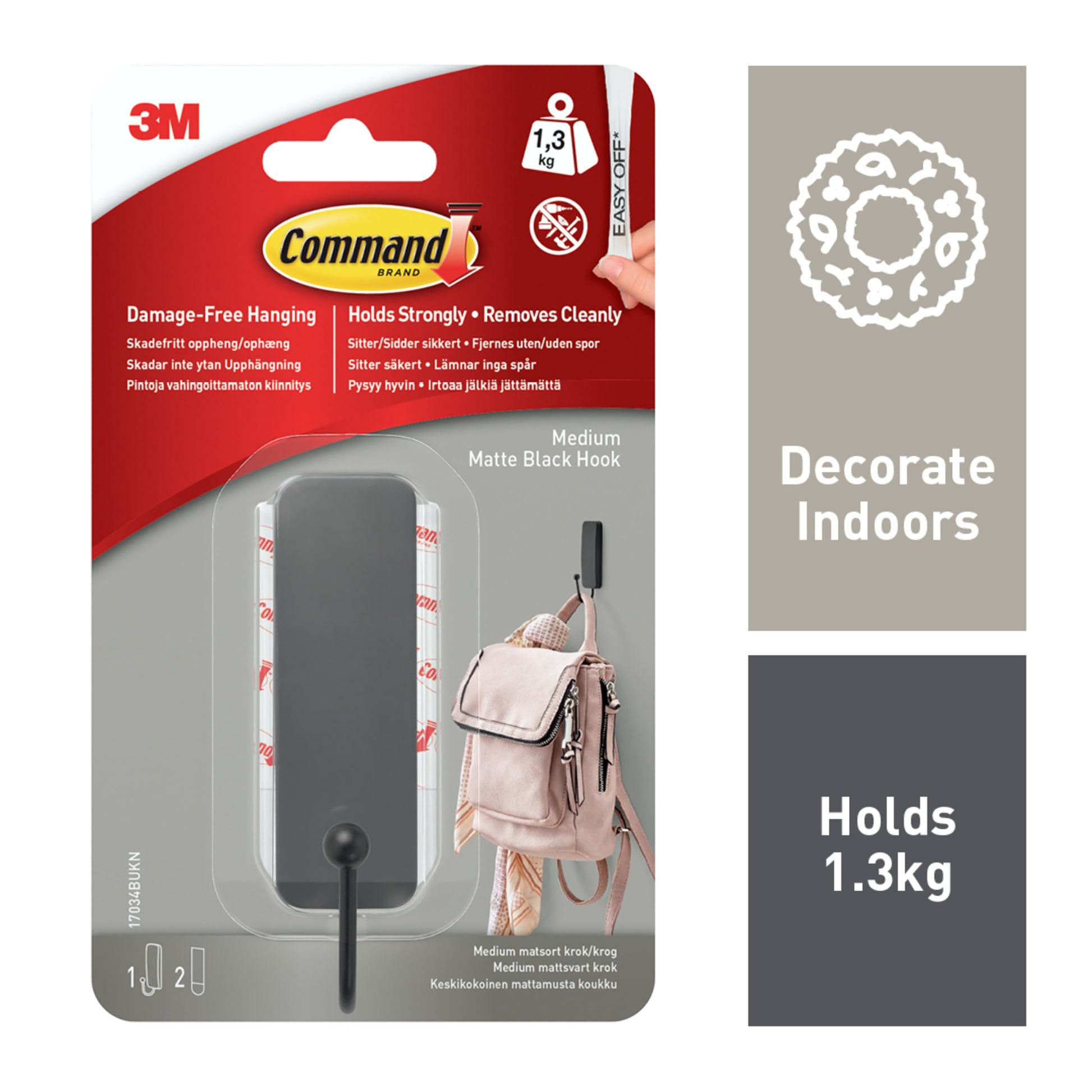 Der mittelgroße Command™ mattschwarze Haken (17034B) von 3M Deutschland GmbH wird in Originalverpackung gezeigt: Er trägt bis zu 1,3 kg, ist leicht ablösbar und für den Innenbereich geeignet. Ein Bild zeigt den Haken mit einer Tasche.